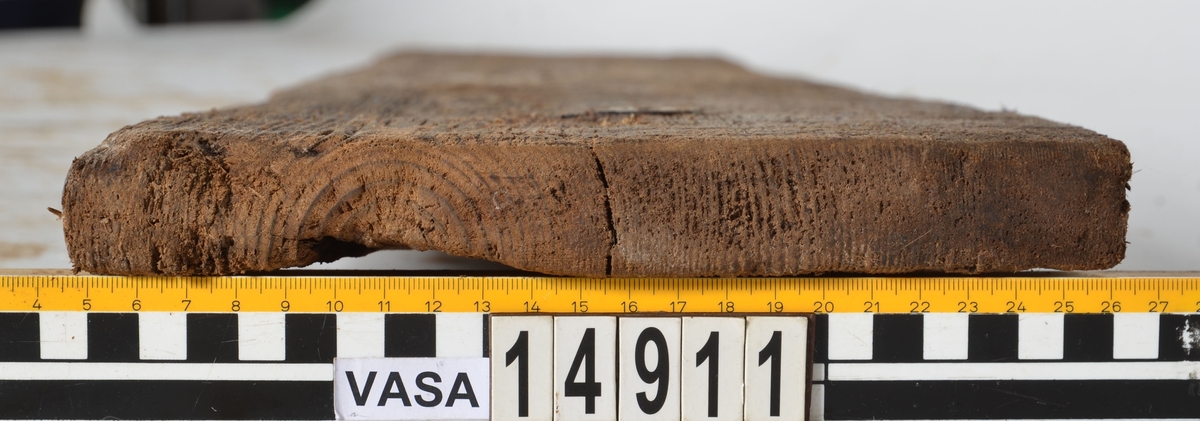 Bräda som tillhör alpumpkistan i hålskeppet. Stor längsgående spricka vilken separerar detta föremål från 14734. En del skador på kanterna.