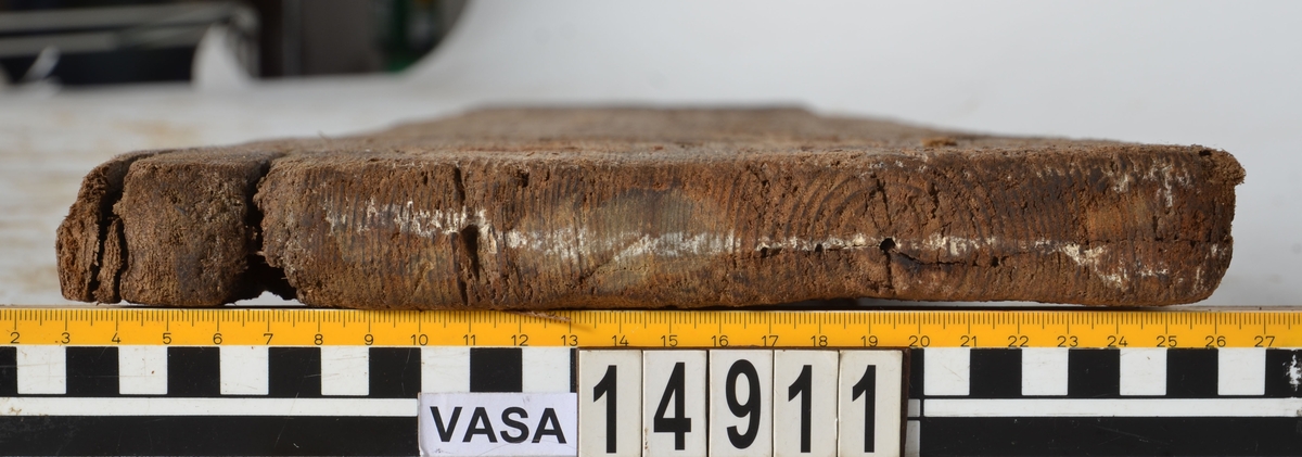 Bräda som tillhör alpumpkistan i hålskeppet. Stor längsgående spricka vilken separerar detta föremål från 14734. En del skador på kanterna.