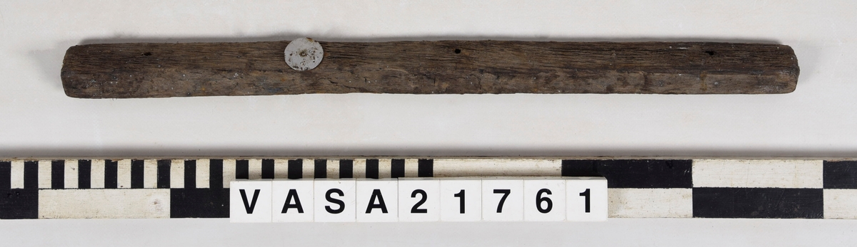 List med en vinklad yta och tre spikhål.
Mycket vittrad i ändarna. Flagnar, mycket torr.