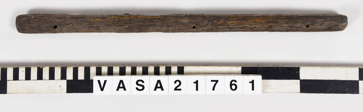 List med en vinklad yta och tre spikhål.
Mycket vittrad i ändarna. Flagnar, mycket torr.