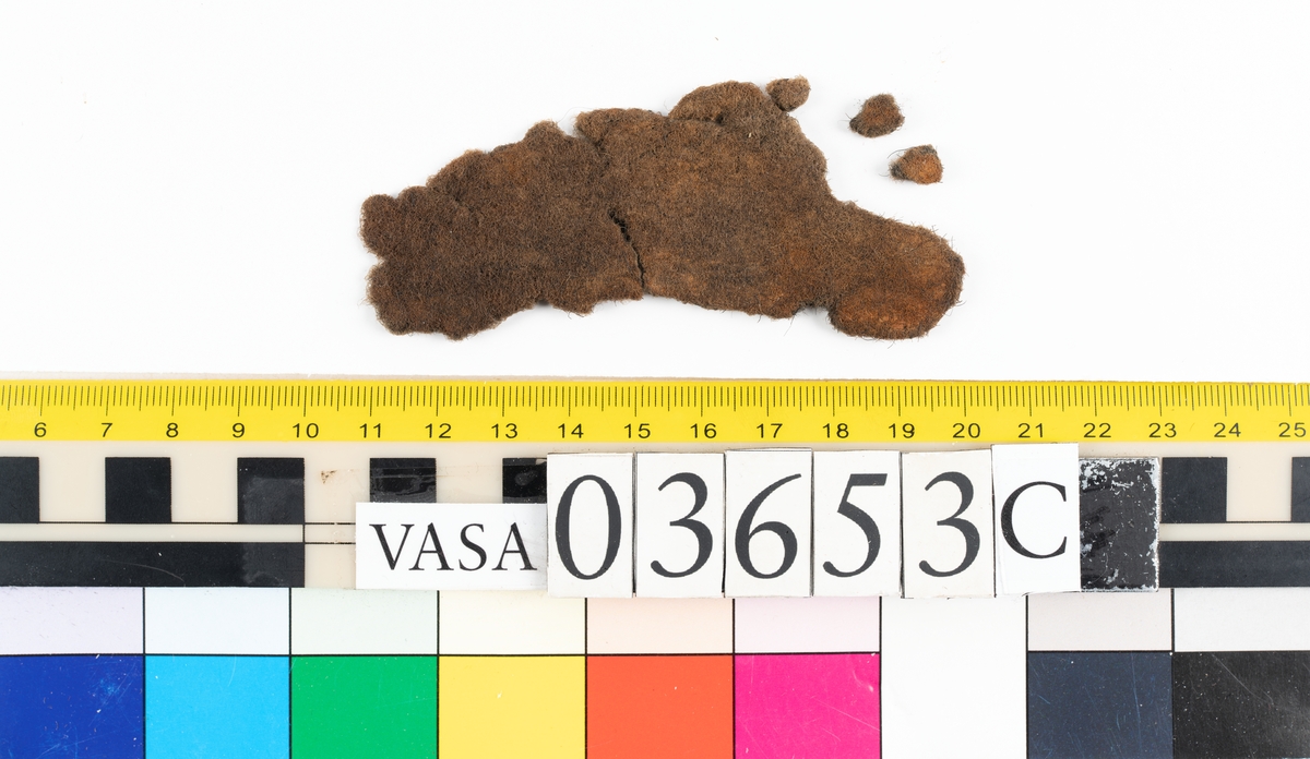 Textilfragment. Fem fragment uppdelade på 03653a-c. Fnr 03653a omfattar tre fragment i ull vävda i tuskaft som ser ut att ha varit valkade. De har idag en brun färg.
Fnr 03653b är ett fint/tunt fragment som är grått med rostfläckar. Fragmentet är av ull vävt i tuskaft och ser ut att ha varit valkat.
Fnr 03653c är filt och har idag en brun färg.


Textildokumentation 2018:


Ingår i kontextgrupp: ÖB31

Fyndnumret 03653a  innehåller 3 fragment av två typer (ÖB31.1:1-2, ÖB31.2:1).
Tygerna är tätt vävda med ruggade ytor. Invasiva fibrer, löst liggande, av ljus kulör finns på alla tre fragmenten. Tygerna är snarlika men skiljer sig bl.a åt vad det gäller trådtäthet.

ÖB31.1:1-2 har slitna kanter samt bortnött lugg på vissa ställen. 
ÖB31.1:1 Ett rostigt avtryck i form av en dubbelbåge, möjligtvis av en hyska  eller en hake. Inga stygnhål syns. Tillskurna kanter på tre sidor. Antydan till tillskuren svängd kant med bristningar utefter en söm. 
ÖB31.1:2 Ett hörn med förhårdnad av rost. Ena sidan har bevarad lugg men andra sidan bortsliten lugg. Ett svagt avtryck i form av en dubbelbåge, möjligtvis av en hyska  eller en hake tillsammans med stygnhål. Antydan till tillskurna kanter på två sidor.
ÖB31.2:1 Bevarade tillskurna kanter varav två med stygnhål och spår av kaststygn. En del stygnhål har rester av rost. På ena sidan finns ett avtryck i form av ett C.  


TEKNIK Typ.nr: ÖB31.1:1-2
Teknik
Trådsystem 1
Trådtäthet (tr/cm): 9-11
Garn nr: 1
Fibermaterial: ull
Garngrovlek (mm): 0,9-1,1
Antal trådar: 1
Spinnriktning: s
Spinnvinkel (grader): 18,3-30,7
Färg:  brun, originalfärg okänd

Trådsystem 2
Trådtäthet (tr/cm): 9-11
Garn nr: 2
Fibermaterial: ull
Garngrovlek (mm): 0,7-0,9
Antal trådar: 1
Spinnriktning: z
Spinnvinkel (grader): 24,8-35,4
Färg: brun, originalfärg okänd

TEKNIK Typ.nr: ÖB31.2:1
Trådsystem 1
Trådtäthet (tr/cm): 10-11
Garn nr: 1
Fibermaterial: 
Garngrovlek (mm): 0,7-0,9
Antal trådar: 1
Spinnriktning: z
Spinnvinkel (grader): -
Färg:  brun, originalfärg okänd

Trådsystem 2
Trådtäthet (tr/cm): 10-11
Garn nr: 2
Fibermaterial: ull
Garngrovlek (mm): 0,7-1,0
Antal trådar: 1
Spinnriktning: s
Spinnvinkel (grader): -
Färg: brun, originalfärg okänd

Fyndnumret 03653b  innehåller 1 fragment (ÖB31.3:1).
Ett mycket tätt vävt tyg med lugg i en ljusare kulör. Ytbehandlad på båda sidorna. På ena sidan är luggen slät och blank samt lutar i en riktning.
Bevarade tillskurna kanter på fyra av fem sidor. Fält med avtryck av rost. Ljusare på ena sidan.


TEKNIK Typ.nr: ÖB31.3:1
Trådsystem 1
Trådtäthet (tr/cm): 27-29
Garn nr: 1
Fibermaterial: ull
Garngrovlek (mm): 0,18-0,22
Antal trådar: 1
Spinnriktning: s
Spinnvinkel (grader): 29-35
Färg: originalfärg okänd 

Trådsystem 2
Trådtäthet (tr/cm): 23-26
Garn nr: 2
Fibermaterial: ull
Garngrovlek (mm): 0,18-0,26
Antal trådar: 1
Spinnriktning: z
Spinnvinkel (grader): 30
Färg: originalfärg okänd


Fyndnumret 03653c  innehåller 1 större samt två mindre fragment. (ÖB31.4:1).
En textil av filtad ull.  Avtryck av järn.

TEKNIK Typ.nr: ÖB31.4:1
Fibermaterial: ull, tunna brunna med inslag av mörkare tjockare fibrer.
Färg: olika nyanser av brunt


Dokumenterad av JH nov 2017, AS maj 2018.
Införd av MS juni 2018.