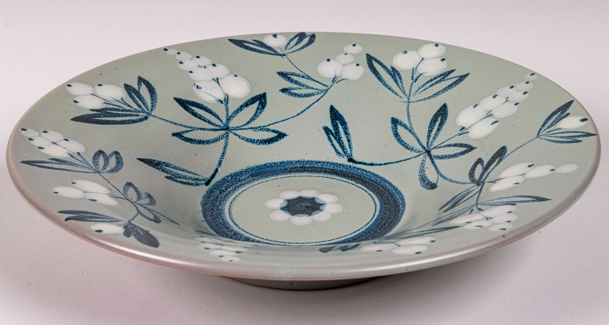 Handmålad skål i modell 4308 med dekor BV; med blå och vita bärkvistar på duvblå botten, blå rand i botten. Formgiven av konstnär Eva Jancke-Björk 1934.