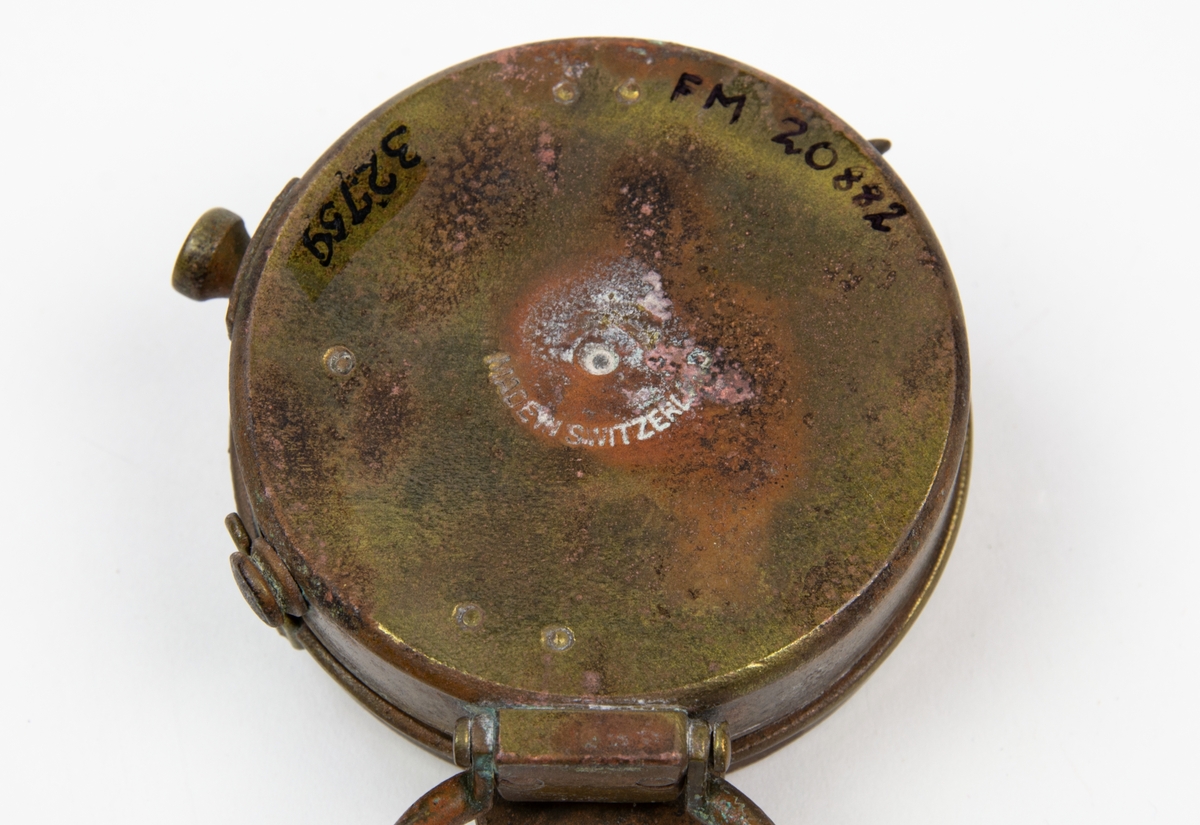 Fickkompass, US Engineer Corps. Tillverkad i Schweiz. Kompasshus och lock i brons. Fluorecerande nordpil och kurspil. Fästögla med läderrem.