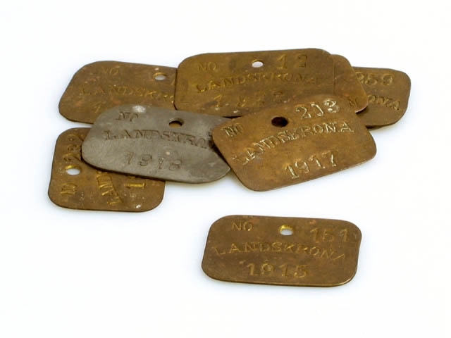 Nio st metallbrickor med nummer, årtal och texten Landskrona. Alla utom två är i gul metall. Årtalen går från 1913-1922, (ej 1920). Brickorna har alla ett hål för att hänga på krok eller möjligen i en kedja. Okänt användningsområde. Brickorna är funna i ett hus i Borstahusen.