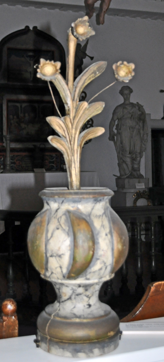 Fra protokollen (Hoel):
Trevase med fritstaaende blomsterprydelser, enten fra prækestolhimlen eller fra korrekkverket i Solum kirke.