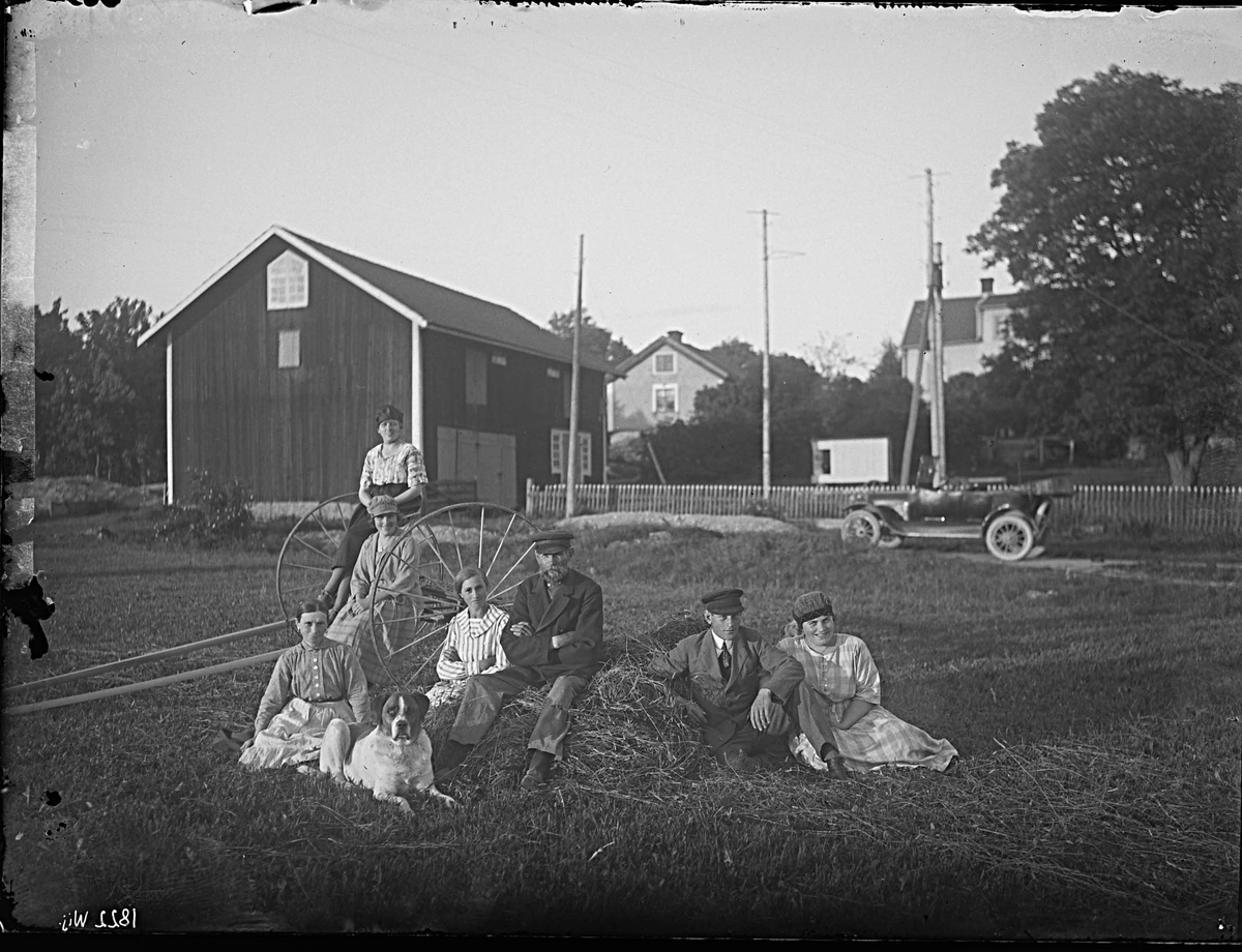 Fotografering beställd av Karlsson. Föreställer sannolikt hemmansägaren Lars Petter Karlsson (1861-1936) på höstacken, och till vänster om hunden hans hustru Anna Katarina Andersson (1866-1947). Övriga personer är ej identifierade.