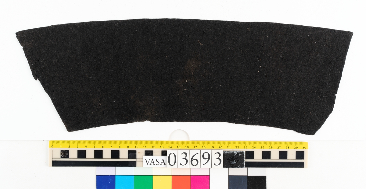 Textil.
2 tillskurna bitar av mörkbrun tät, hård filt. Små runda hål syns på ett flertal ställen på fragmenten, troligen från olika sömmar.

Textildokumentation 2018:

Ingår i kontextgrupp: ÖB31
Fyndnumret 03693 innehåller 2 fragment (ÖB31.5:1-2). Fyndnumret innehåller även ett tråd.
Fragmenten är av filtad ull i mycket fin kvalitet och med en tät filtning. Fragmenten är tillskurna. Det finns tydliga märken efter stygn och stygnhål utefter kanterna. Ca 10 st runda hål, möjligen stansade.
På ena sidan av båda delarna finns snedställda avtryck som liknar avtryck från snedställda pikéringsstygn. Delarna är tillskurna och har jack utefter kanterna som skulle kunna vara passmärken. Spår av kastsöm på delar av kanterna.
Materialet är stelt som om det skulle kunna vara behandlat med något. Ingen tydlig lukt.
Delarnas ena sida har en slätare struktur. 
ÖB31.5:2. På tvären finns spår av ett veck. Vid vecket ett blekt område. Utefter kanter bristningar. 
Det finns små tryckmärken alt. märken av skadeddjur.

Tråden är tunn och vågig, möjlig del av tjockare tråd. 

TEKNIK Typ.nr: ÖB31.5:1-2
Fibermaterial: ull
Garngrovlek (mm): 0,7-0,9
Färg: mycket mörk, möjlig svart

TEKNIK Typ.nr: (ÖB31.5:1-2) tråd:
Antal tråd: 1
Fibermaterial: ull
Spinnriktning: z
Färg: svart

Dokumenterad av AS nov 2017, maj 2018.
Införd av MS juli 2018.