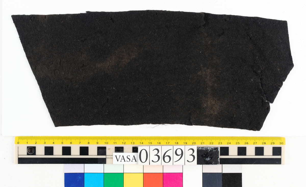 Textil.
2 tillskurna bitar av mörkbrun tät, hård filt. Små runda hål syns på ett flertal ställen på fragmenten, troligen från olika sömmar.

Textildokumentation 2018:

Ingår i kontextgrupp: ÖB31
Fyndnumret 03693 innehåller 2 fragment (ÖB31.5:1-2). Fyndnumret innehåller även ett tråd.
Fragmenten är av filtad ull i mycket fin kvalitet och med en tät filtning. Fragmenten är tillskurna. Det finns tydliga märken efter stygn och stygnhål utefter kanterna. Ca 10 st runda hål, möjligen stansade.
På ena sidan av båda delarna finns snedställda avtryck som liknar avtryck från snedställda pikéringsstygn. Delarna är tillskurna och har jack utefter kanterna som skulle kunna vara passmärken. Spår av kastsöm på delar av kanterna.
Materialet är stelt som om det skulle kunna vara behandlat med något. Ingen tydlig lukt.
Delarnas ena sida har en slätare struktur. 
ÖB31.5:2. På tvären finns spår av ett veck. Vid vecket ett blekt område. Utefter kanter bristningar. 
Det finns små tryckmärken alt. märken av skadeddjur.

Tråden är tunn och vågig, möjlig del av tjockare tråd. 

TEKNIK Typ.nr: ÖB31.5:1-2
Fibermaterial: ull
Garngrovlek (mm): 0,7-0,9
Färg: mycket mörk, möjlig svart

TEKNIK Typ.nr: (ÖB31.5:1-2) tråd:
Antal tråd: 1
Fibermaterial: ull
Spinnriktning: z
Färg: svart

Dokumenterad av AS nov 2017, maj 2018.
Införd av MS juli 2018.
