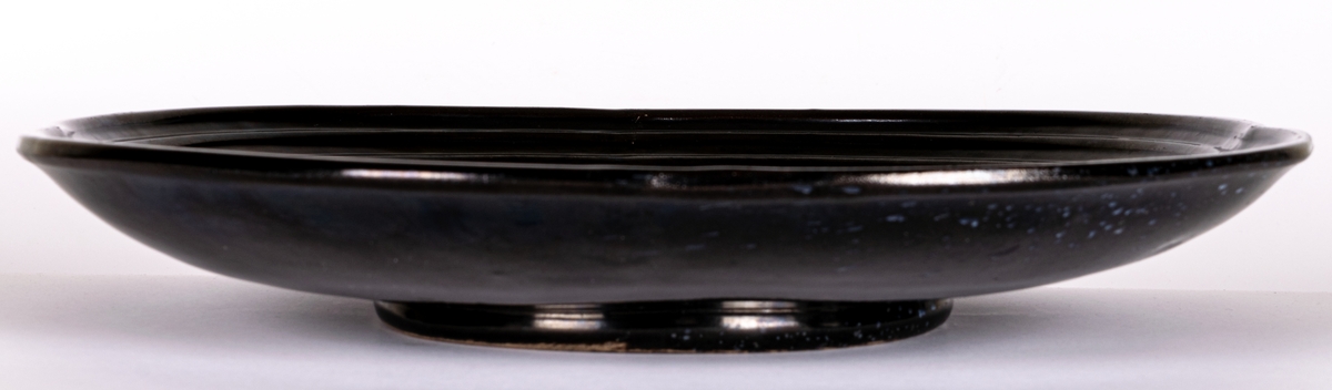 Stort svartglaserat fat, kallat "fyrklöverfat", av lergods, av Ewald Dahlskog, Bo Fajans. Modell D1.