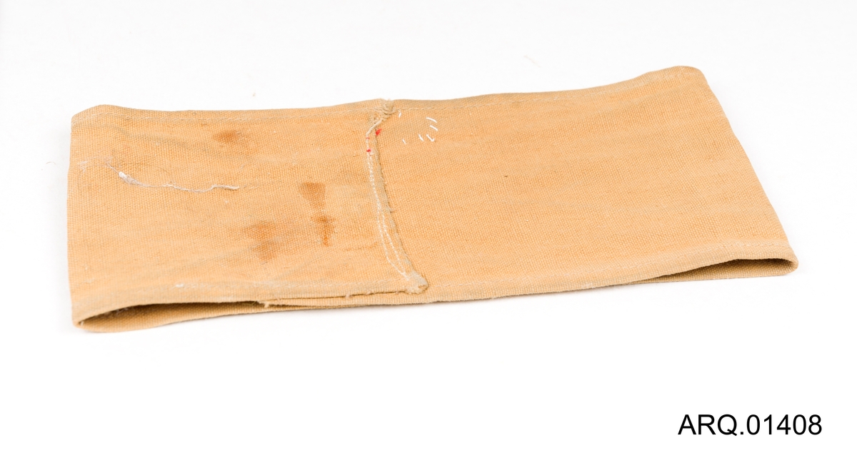Armbind i seildukstoff, lysegult med påsydd norsk flagg og 3 røde striper.