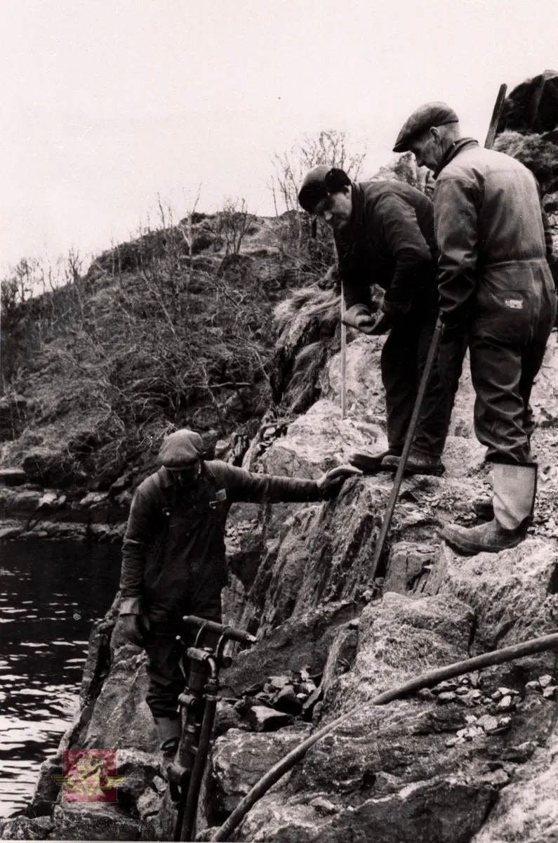 Byggjing av Måløybrua åra 1972 - 1973.

Vegvesenet sine folk gjer klar til sprengjing for fundament til søyle 24.

Vegarbeidet på fastlandet tok til i oktober 1970. Bruentreprisen byrja i november 1971 og hovedentreprenør var Eeg Henriksen AS. I januar 1972 tok støypinga til og i desember 1973 stod brua klar for trafikk. Brua vart offisielt opna 11. juni 1974 av H.M. Kong Olav.

Måløybrua er ei spennbetongbru med to hovedspenn over skipsleia, kvar på 125 meter, i tillegg til to sidespenn 65 meter bygd etter fritt-fram-metoden. Dei fleste av dei 30 andre spenna har 30 meter i spennvidde. Den samla brulengda er 1224 meter. Seilingshøgda i skipsleia er 42 meter. Til brua gjekk det med 1500 tonn armeringsstål, 14 300 m³ betong og 175 000 meter spennkablar. Brua har kurver både i vertikal- og horisontalplanet, noko som gjorde brua komplisert å byggja.

(Kjelde: Boka "På god veg - Veghistorie i Sogn og Fjordane" av Kristin Ese)

Bilete er eit av 95 motiv frå byggjinga av Måløybrua.
