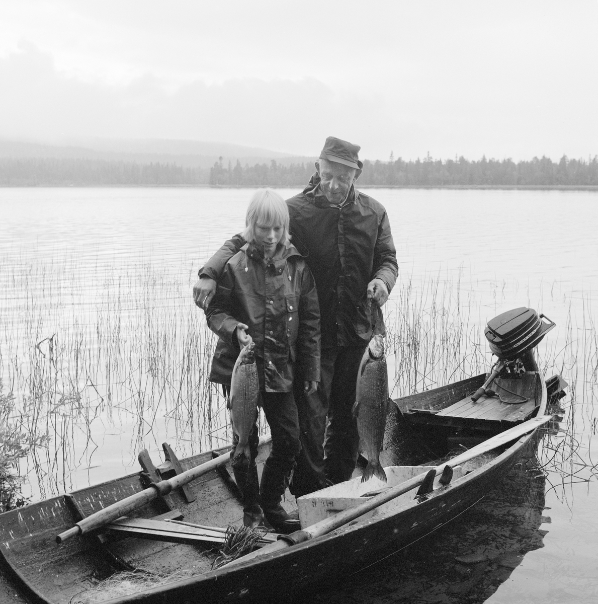 Fiske i Galthåen. Galthåen ligger mellom Isteren og Galtsjøen i Trysilvassdraget, Engerdal, Hedmark. Erling Sand (t.h.) og Torstein Fossum står i båten og holder hver sin digre sik som de har fanget i garn.