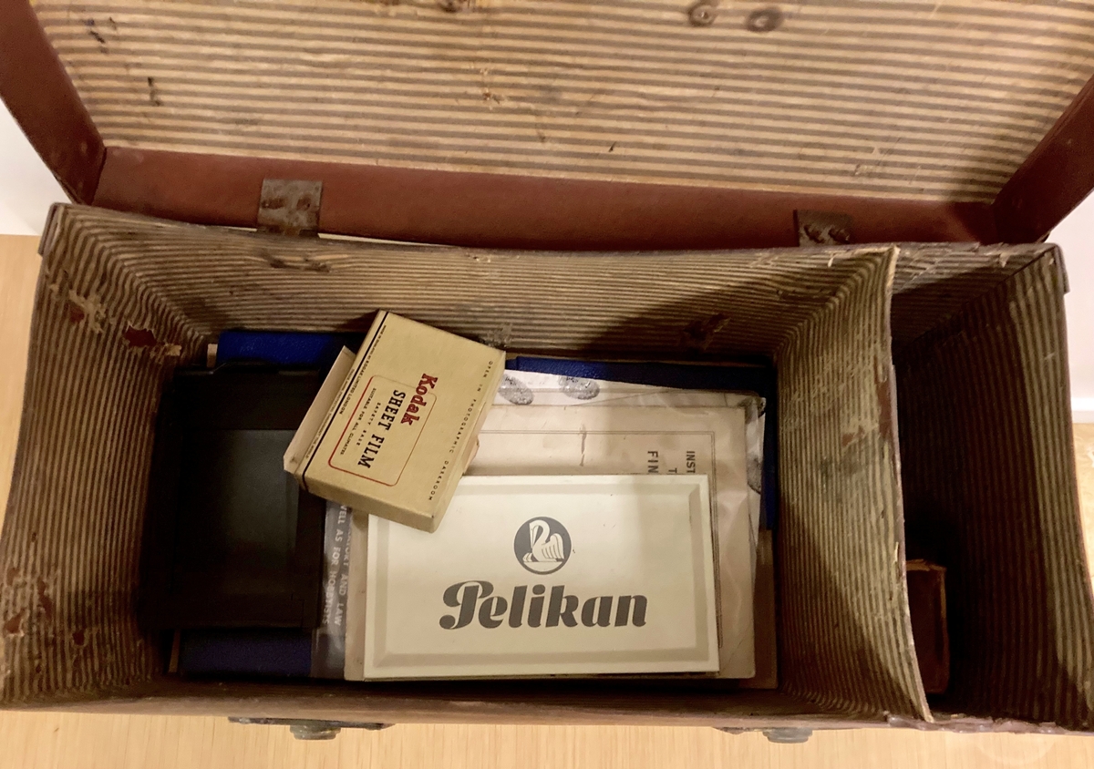 Brun liten koffert med håndtak og låsbar lukkemekanisme.