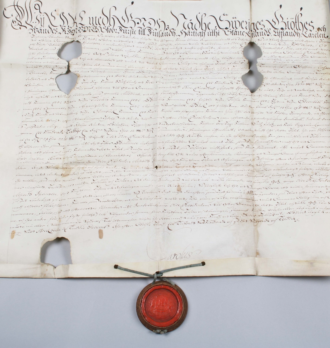 Bytes brev, med tillhörande rött sigill. Handskriven svart text mot vitt papper. Kungligt rött sigill, med Svea rikes vapen, infällt i profilerad träplatta. Brevet skrivet av Kronan1673. Till Arfwid Ifwarson. Signerat: Carolus (Kung Karl XI)

Text börjar med: 
Bytes Bref medh Cronan på Tranwijk, Öfwer by och Humblemohra; Wärmbdöön emoth Godtz i Wästergötlandh. No 13.............

Avslutas med: 
Kong: Slott Stockholm d. Treddie Decemb Åhr efter Christi bördh, Ett Tusendh Sexhundrade och på dhet Siuttijonde och Tridie. Carolus.

Anm: Se hela texten översatt i bildrutan