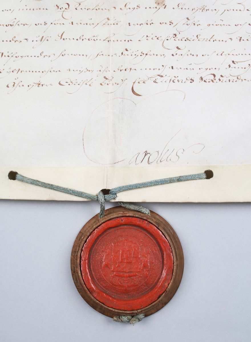 Bytes brev, med tillhörande rött sigill. Handskriven svart text mot vitt papper. Kungligt rött sigill, med Svea rikes vapen, infällt i profilerad träplatta. Brevet skrivet av Kronan1673. Till Arfwid Ifwarson. Signerat: Carolus (Kung Karl XI)

Text börjar med: 
Bytes Bref medh Cronan på Tranwijk, Öfwer by och Humblemohra; Wärmbdöön emoth Godtz i Wästergötlandh. No 13.............

Avslutas med: 
Kong: Slott Stockholm d. Treddie Decemb Åhr efter Christi bördh, Ett Tusendh Sexhundrade och på dhet Siuttijonde och Tridie. Carolus.

Anm: Se hela texten översatt i bildrutan