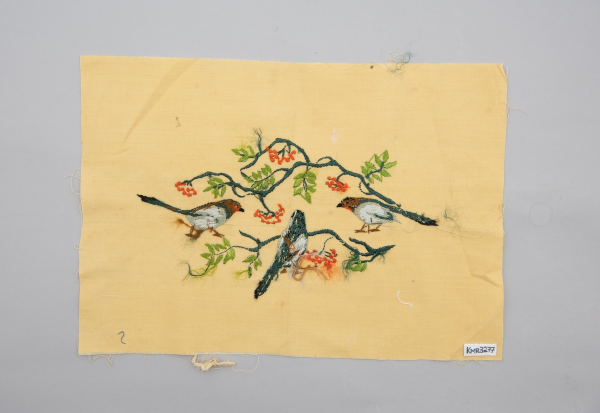 Brodert veggbilde med fuglemotiv. Tre fugler og to greiner med rognebær.