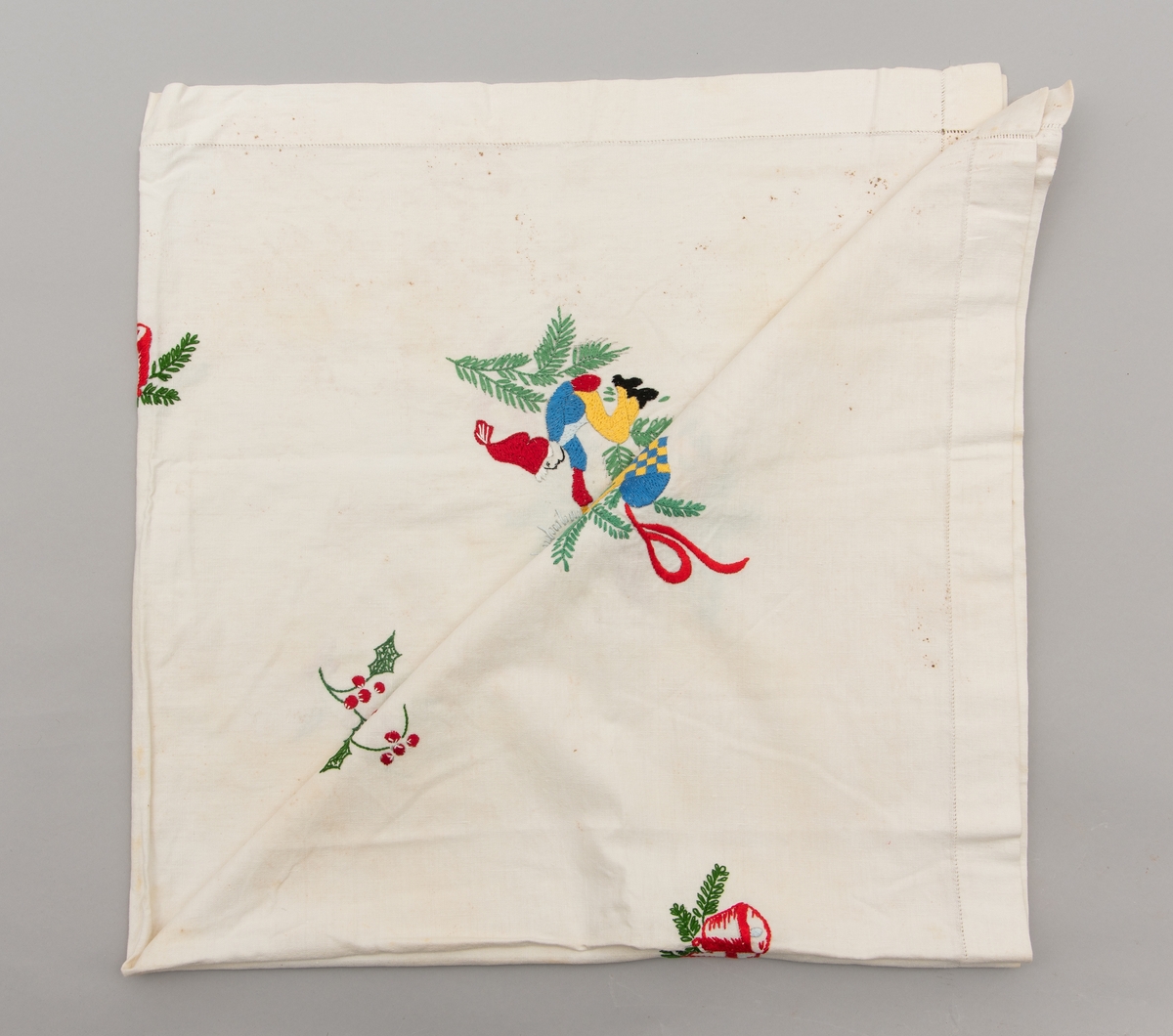 Hvit duk med julemotiver brodert på. Det er brodert julekurver med fargene i det svenske flagget.