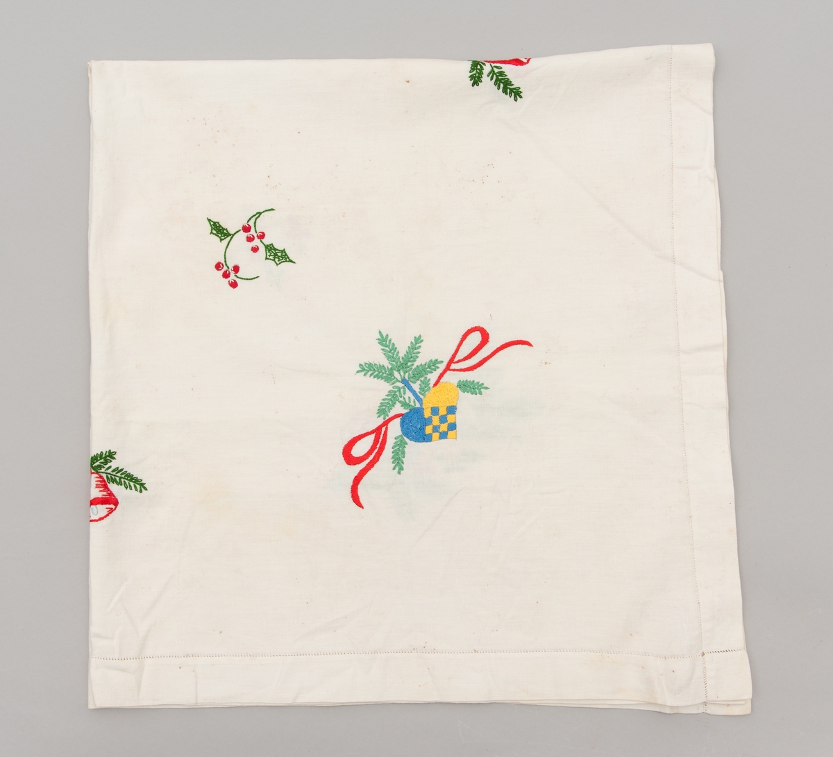 Hvit duk med julemotiver brodert på. Det er brodert julekurver med fargene i det svenske flagget.