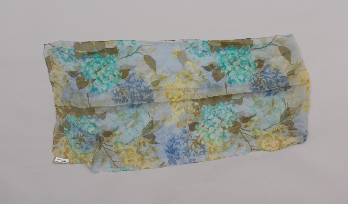 En grå-beige draktkjole og to tynne fargede sjal. Drakta er tredelt med bluse, skjørt og jakke. Drakt og sjal ble brukt sammen.