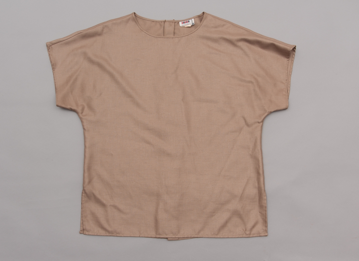 En grå-beige draktkjole og to tynne fargede sjal. Drakta er tredelt med bluse, skjørt og jakke. Drakt og sjal ble brukt sammen.