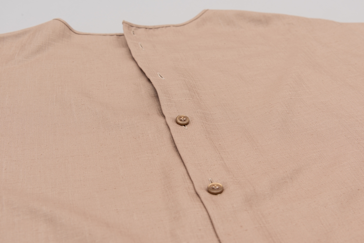 En grå-beige draktkjole og to tynne fargede sjal. Drakta er tredelt med bluse, skjørt og jakke. Drakt og sjal ble brukt sammen.