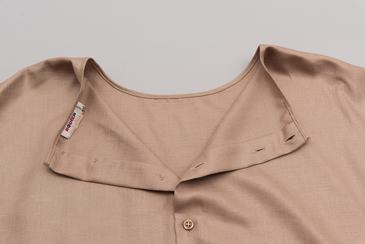 En grå-beige draktkjole og to tynne fargede sjal. Drakta er tredelt med bluse, skjørt og jakke. Drakt og sjal ble brukt sammen.