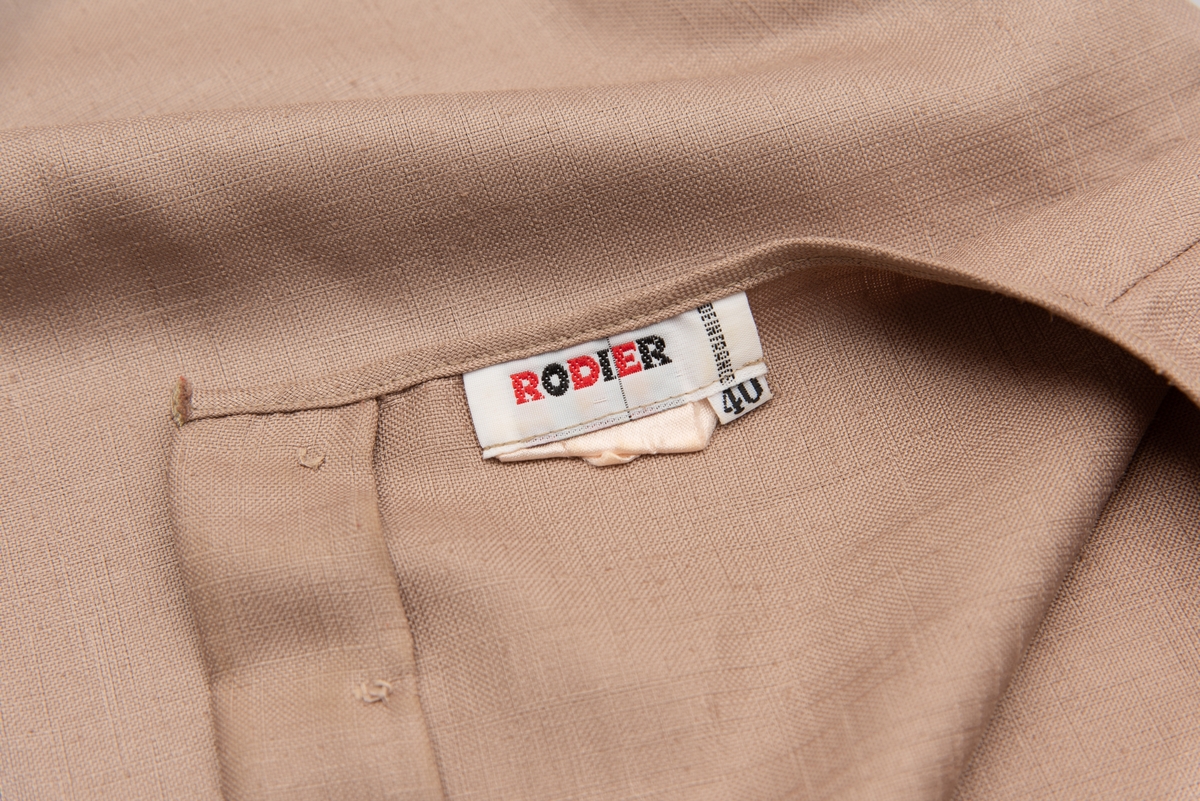 En grå-beige draktkjole og to tynne fargede sjal. Drakta er tredelt med bluse, skjørt og jakke. Drakt og sjal ble brukt sammen.