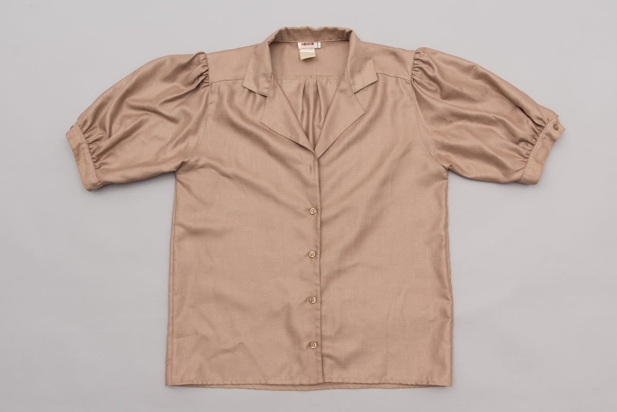 En grå-beige draktkjole og to tynne fargede sjal. Drakta er tredelt med bluse, skjørt og jakke. Drakt og sjal ble brukt sammen.