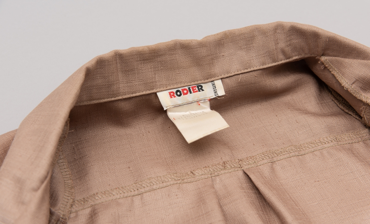 En grå-beige draktkjole og to tynne fargede sjal. Drakta er tredelt med bluse, skjørt og jakke. Drakt og sjal ble brukt sammen.