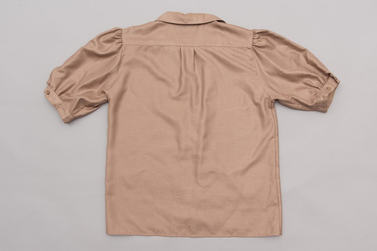 En grå-beige draktkjole og to tynne fargede sjal. Drakta er tredelt med bluse, skjørt og jakke. Drakt og sjal ble brukt sammen.