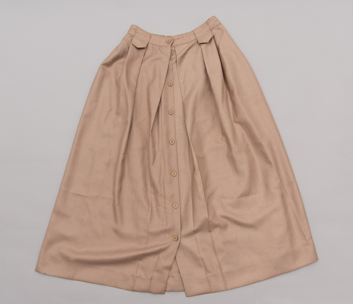 En grå-beige draktkjole og to tynne fargede sjal. Drakta er tredelt med bluse, skjørt og jakke. Drakt og sjal ble brukt sammen.