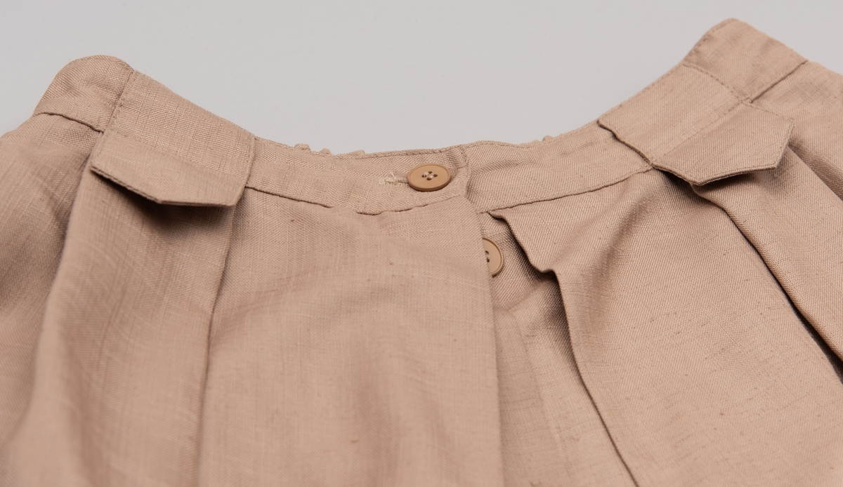 En grå-beige draktkjole og to tynne fargede sjal. Drakta er tredelt med bluse, skjørt og jakke. Drakt og sjal ble brukt sammen.