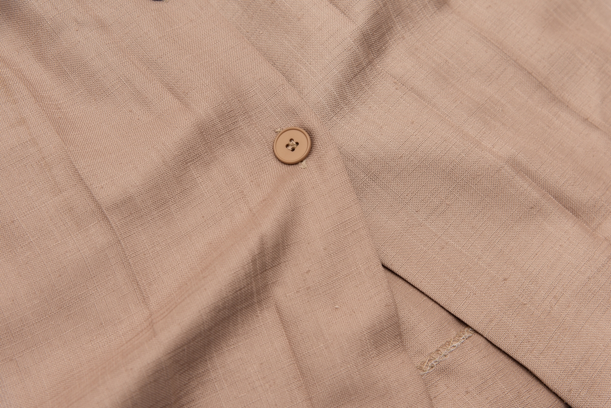 En grå-beige draktkjole og to tynne fargede sjal. Drakta er tredelt med bluse, skjørt og jakke. Drakt og sjal ble brukt sammen.