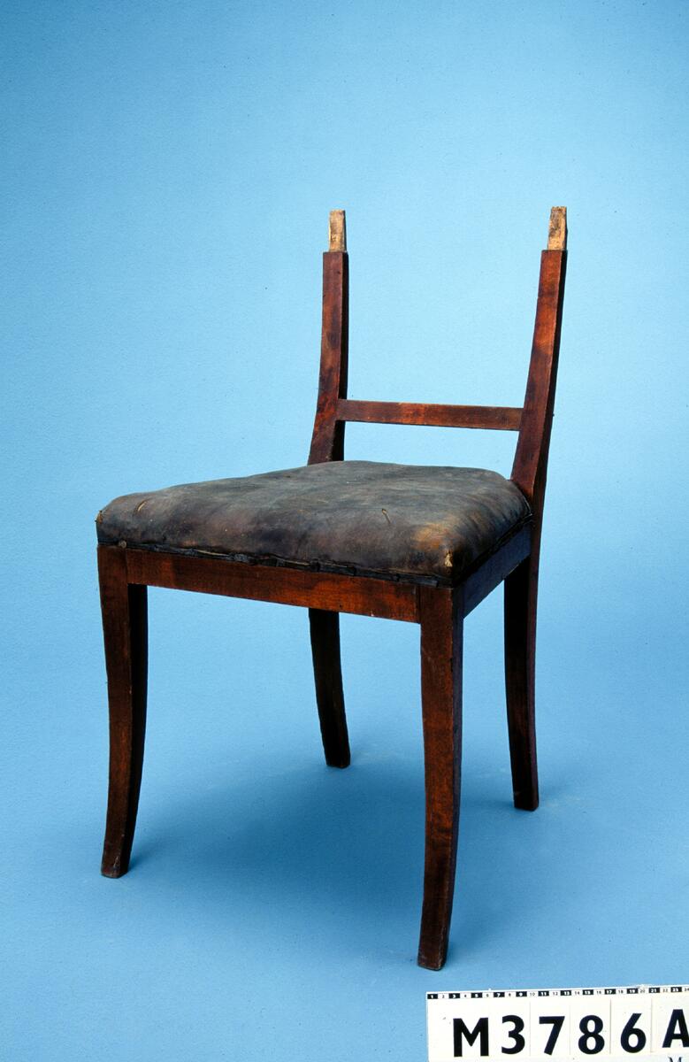 Fyrkantiga, något svängda och konade ben. Sargen är rak. Sitsen är stoppad och klädd i ett grönt tyg. Ett grönt möbelband går runt klädseln. Ryggstycket består av raka och konade ryggståndare, ett rakt och liggande överstycke samt en ryggbricka i form av ett lövblad och stiliserade voluter. Stolen är brunmålad. Emipre. Polerad i mahognyfärg. Fyrkantiga något utsvängda ben. Rak sarg. Böjd formad rygg har raka sidoståndare med tvärslå samt horisontalt, 10 cm brett överstycke och lodrät mittslå. Höjd 82 cm. Rygghöjd 38 cm. Sitsdjup 41 cm. Härnösand. Anm. Enl. intyg skall stolarna ha tillhört biskop F.M. Franzén. Inköpt: J Åmell. 