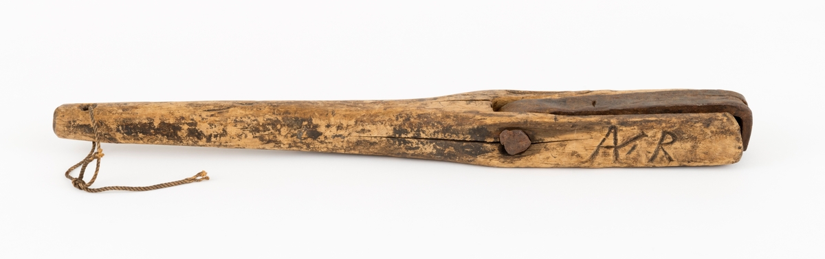 Såkalt bandhake, et redskap som ble brukt når det skulle settes band på tønner. Det har en 52,8 centimeter lang hendel av tre, sannsynligvis av bjørkevirke. Denne komponenten er noenlunde oval og forholdsvis smal (2,6-3,0 centimeter) i den ene enden. Tjukkelsen øker gradvis mot den andre enden, som har et rektangulært tverrsnitt (6,6 X 4,2 centimeter) i cirka 19 centimeters lengde. På den ene flatsida av dette rektangulære endestykket er det nedfelt et spor der det er innhengslet ei cirka 19,5 centimeter lang og snaut 3 centimeter bred jernstang med ytterende som er vinklet framfor enden av treskaftet. Denne komponenten er dreibar omkring en spiker som er innslått på tvers av det rektangulære endestykket, gjennom den indre delen av den nevnte utsparinga. I den smale enden av bandhaken, handtaksenden, er det et gjennombrutt hull med ei opphengssnor.

Gjenstanden oppgis å være laget før 1850 av Anders Klausen Hysingjord fra Nordreisa. Initialene «AR» er innskåret på ei av sideflatene. På ei anna flate finner vi bokstaven «A».
