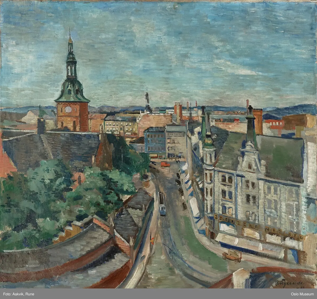 Sette fra taket på hjørnegården til Storgata. Rett fram svingen opp til Stortorget. Til h. Doblouggården. Til v. basarene og Vår Frelsers kirke (Domkirken) med grøt spir. Gata malt Grønlia med blå trikkeskinner og blå trikk. På hjørnet av Torget. en rød varebil. Bakover sees hustak i forskjellige farger med blå åser i bakgrunnen. 