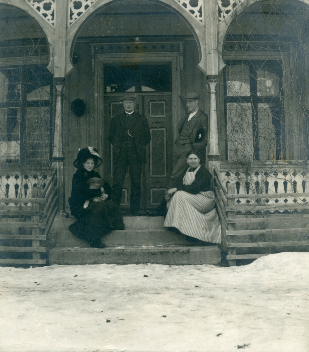 To menn og to kvinner sitjande ute på ein veranda i sveitserstil
Tatt i februar 1912