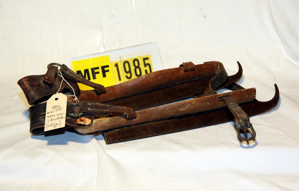 "Skridskor, ett par, som skissen, med skena av järn fotställ av trä i form av en sula bindslen av remmar med söljor av mässing. Längd 34,2 cm. Fotstället 29 x 7 x 2 cm." (skiss) -
"Redan under forntiden färdades man på isytor med "isläggar". Skenorna voro gjorda ursprungligen av ben, senare av järn eller stål, med fotplatta av trä i vilken voro anbragta hål för snören eller remmar till skridskons fästande vid foten. (Nord. familjebok tryckår 1897)" (Ur Lappkatalogen, Arvid Enqvist 1936.)

Skridskor Par: märkt "H - V". (inv.prot.)