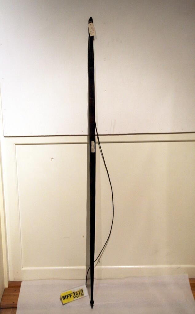 "Pilbåge av trä, som skissen, brun, hård och tung profilerade spetsar sträng av tvinnade och beckade senor. Bågen rak. - Längd 161 cm. Bredd 4 cm. - Fr. Söderhavsöarna. - Gåva av J O Ödlund, Skönsberg." (skiss) (Ur Lappkatalogen. Arvid Enqvist, 1936)

