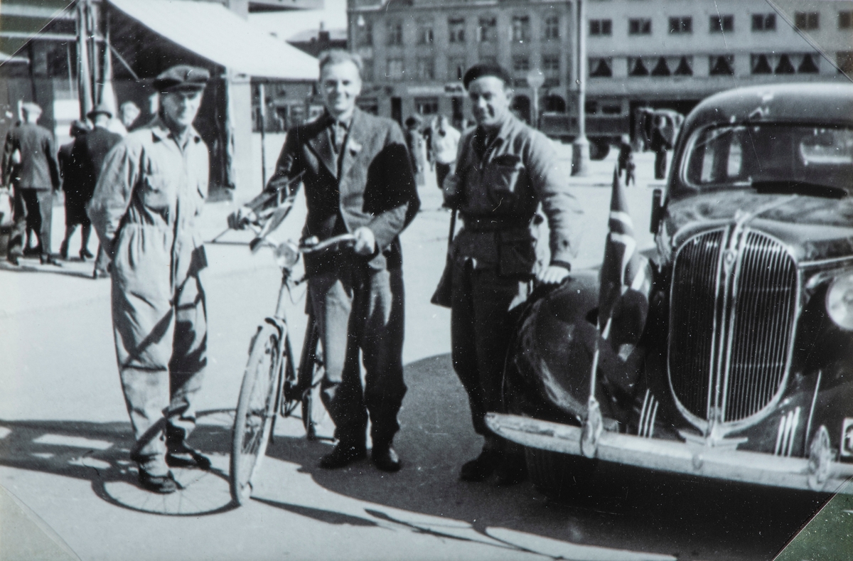 Bilder fra frigjøringsdagene i april og mai 1945. Hjemmefronts folk på Østre Torg, Mann med sykkel og Norskt flagg. Odvar Engstad, Arne Busterud og Arvid Amdahl. Bilen er en Plymouth 1938.