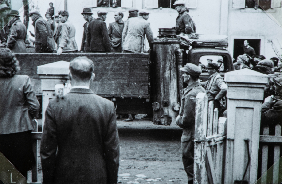 Bilder fra frigjøringsdagene i april og mai 1945. Mye tilskuerer som ser på at en lastebil med arresterte nazister ankommer Hamar fengsel. Lastebil med knott generator.