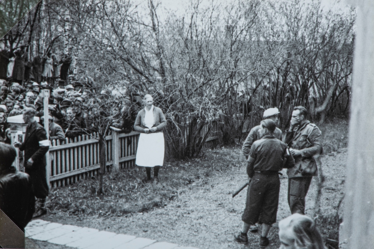 Bilder fra frigjøringsdagene i april og mai 1945. Mye tilskuerer som ser på at en lastebil med arresterte nazister ankommer Hamar fengsel. Fru Bjøralt følger med fra innsiden av gjerdet.