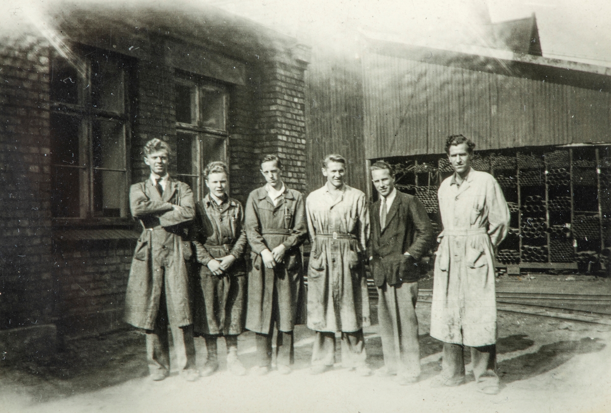 Gruppe 6 arbeidere, ved Hamar Jernstøperi på 1940-tallet. Ham-Jern. Kledd i arbeidsfrakk.  nr 4 fra venstre er Yngve Jørstad, resten er ukjente.