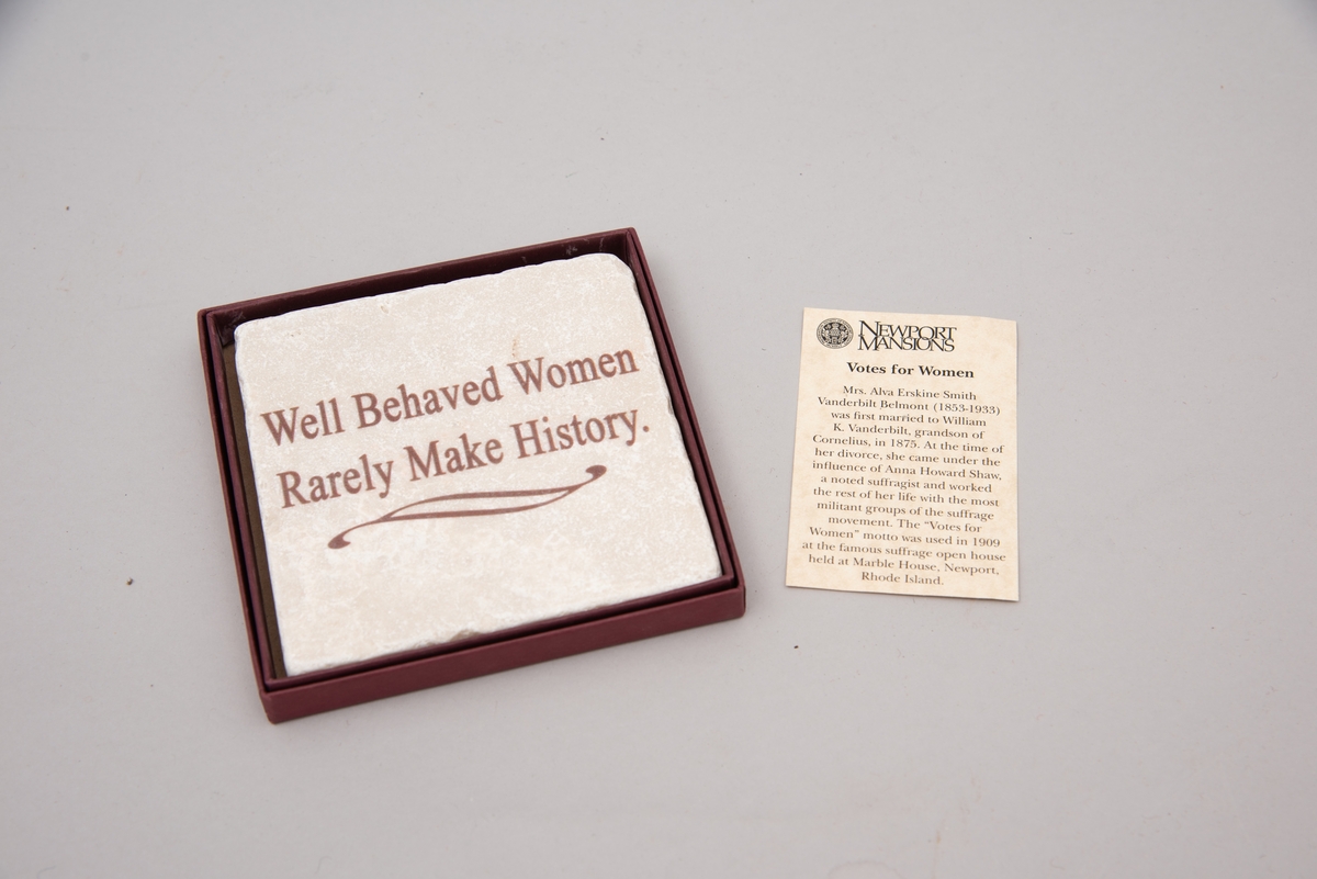 Marmorflis og souvenir fra Newsport Mansions med påført slagord "Well Behaved Women Rarely Make History". Tilhørende eske og informasjonsfolder. Mottoet påført marmorflisa er i ettertida blitt brukt til å beskrive Alva Vanderbilt Belmont (1853-1933) og andre kvinner som kjempet for kvinners stemmerett på begynnelsen av 1900-tallet i USA under slagordet "Votes for Women". Selve "Votes for Women"-mottoet ble brukt i 1909 på et berømt "open house" stemmerettsmøte holdt på Marble House, Newport, Rhode Island".