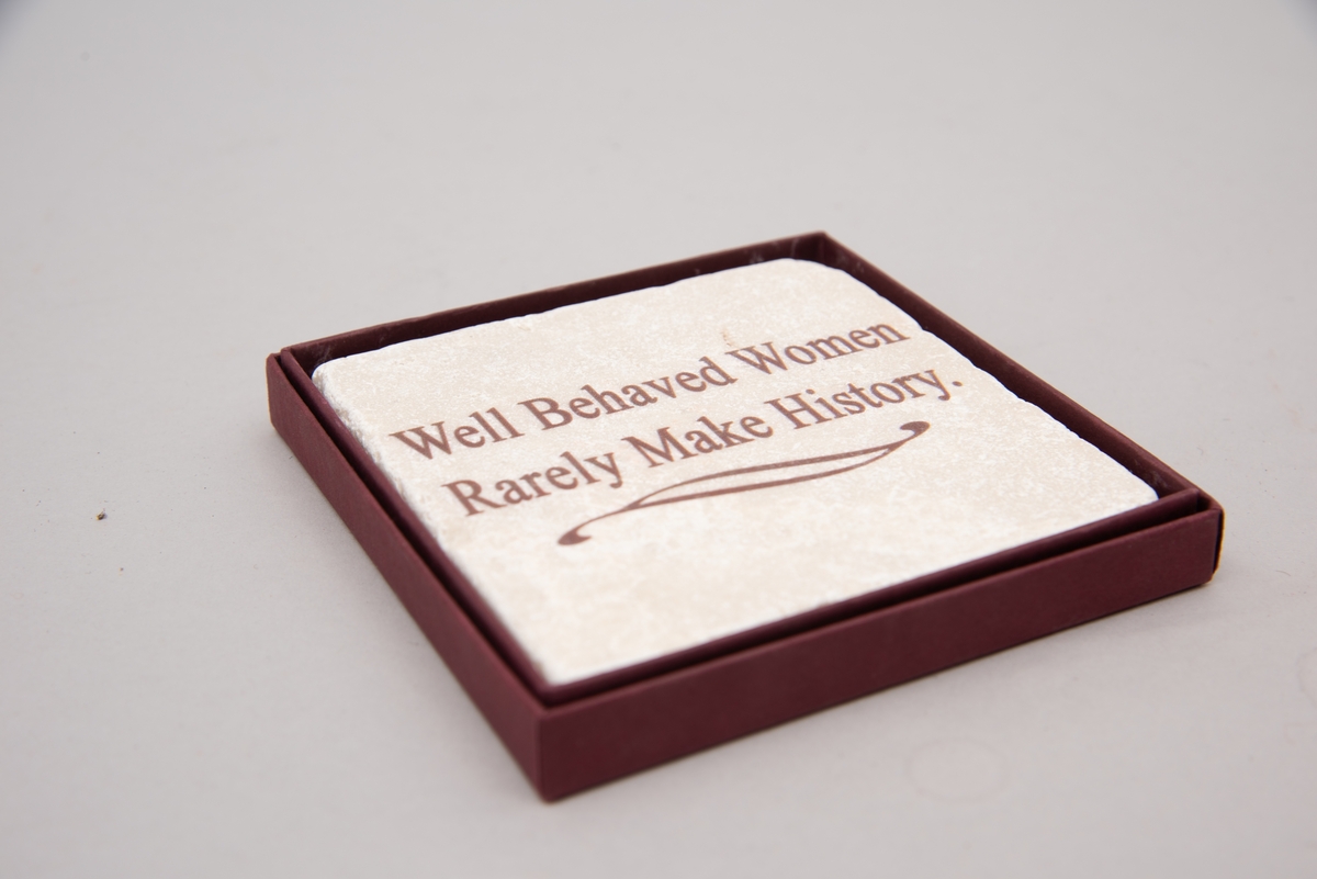 Marmorflis og souvenir fra Newsport Mansions med påført slagord "Well Behaved Women Rarely Make History". Tilhørende eske og informasjonsfolder. Mottoet påført marmorflisa er i ettertida blitt brukt til å beskrive Alva Vanderbilt Belmont (1853-1933) og andre kvinner som kjempet for kvinners stemmerett på begynnelsen av 1900-tallet i USA under slagordet "Votes for Women". Selve "Votes for Women"-mottoet ble brukt i 1909 på et berømt "open house" stemmerettsmøte holdt på Marble House, Newport, Rhode Island".