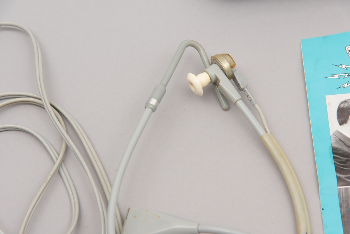 Et sett med øreplugger. Merket er kalt Hodemikrotelefon STETOMIKE. Var levert av Televerket. Produsert av Danavox International.
Settet består av hodetelefon med ledninger og plugg til uttak, samt bruksanvisning, flere typer ekstradeler til selve ørepluggene, samt lukkbar mappe/etui i mørk blå plast.