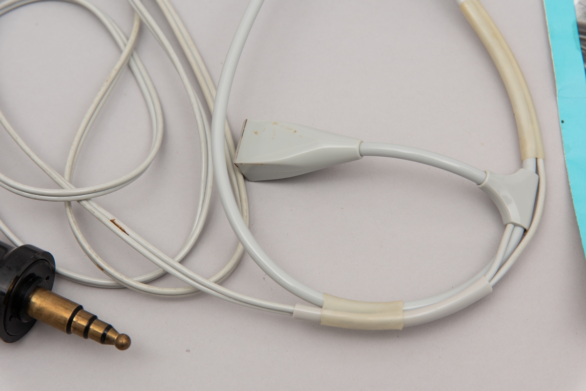 Et sett med øreplugger. Merket er kalt Hodemikrotelefon STETOMIKE. Var levert av Televerket. Produsert av Danavox International.
Settet består av hodetelefon med ledninger og plugg til uttak, samt bruksanvisning, flere typer ekstradeler til selve ørepluggene, samt lukkbar mappe/etui i mørk blå plast.
