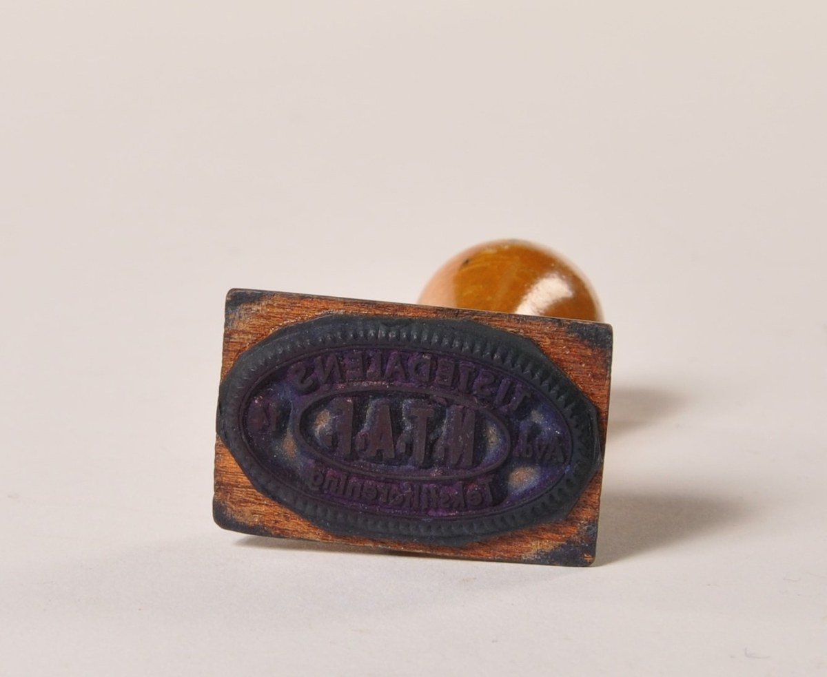 Gummistempel med dreid trehåndtak: Tistedalens Tekstilforening.