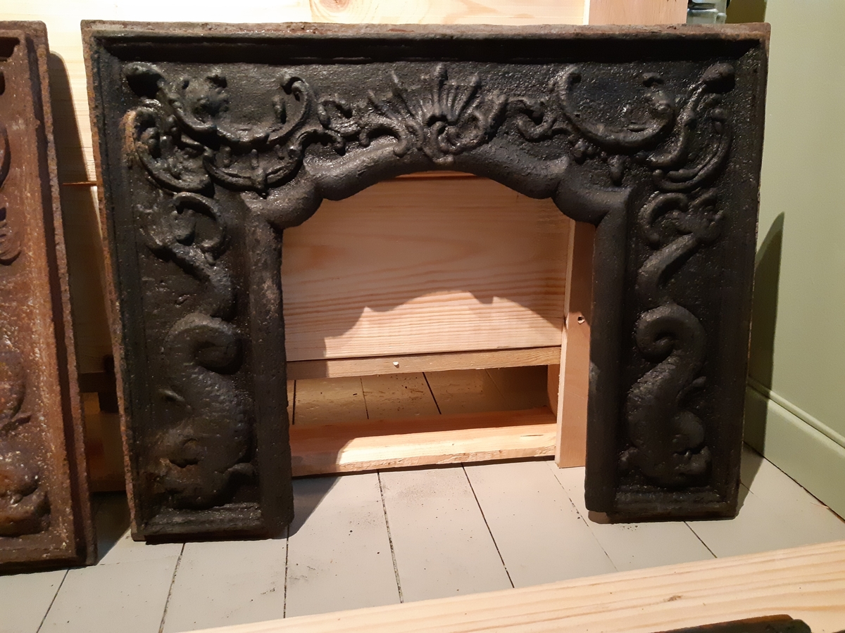 Etasjeovn i støpejern, tre etasjer. Motiv Neptun på fyringskasse. Etasjene med rocailler. Trekrakk, oker farge, kannelerte avsmalnede ben med diamant øverst. 25 deler