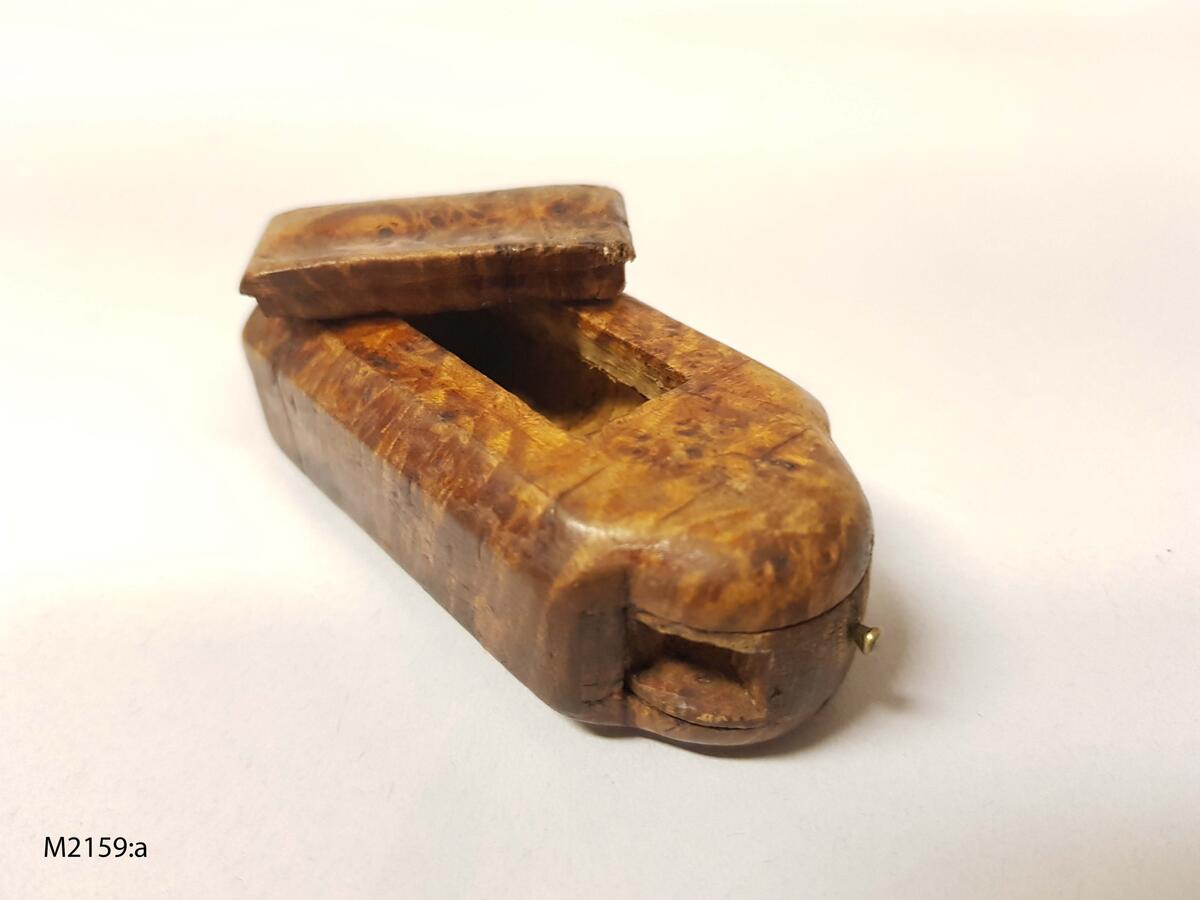 Snusdosa, av masur. Rektangulär med ena kortsidan kraftigt utsvängd. Denna sida med vridbart hjul. Litet lock, märkt 1802. Ramsele socken, Ångermanland. (Ur lappkatalogen).